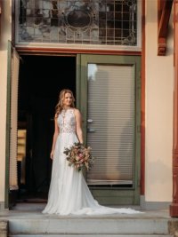 Bruid - staande portretfoto voor deurkozijn buiten