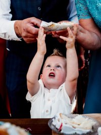 klein jongentje wat met de handjes omhoog staat en heel graag het schoteltje met taart boven zijn hoofd wil pakken