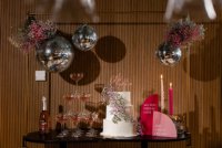 Foto van de taartafel met champagne toren versierd met gekleurde gipskruid bollen en discoballen