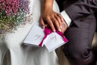 Close up van handen bruidspaar met geloftenboekjes