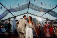 dansend bruidspaar in feesttent met gasten op de achtergrond