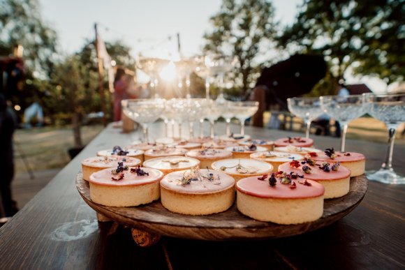 close up sweets, roze tartelettes met op de achtergrond champagnecoupes