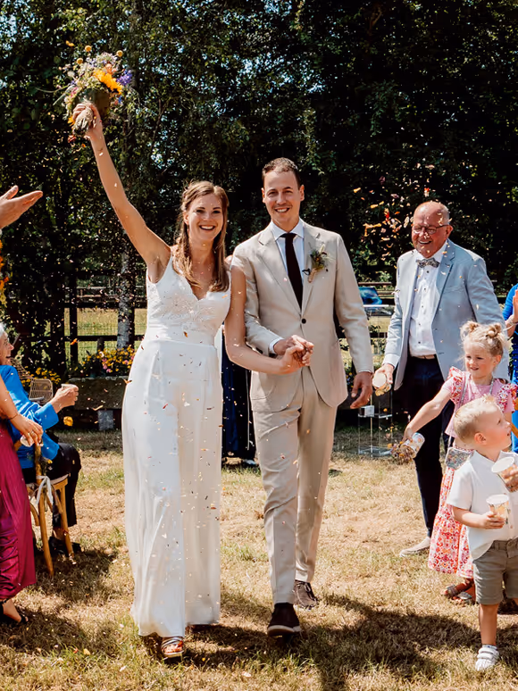 Bruidspaar hand in hand lopend door het gangpad na het einde van de ceremonie