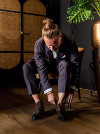 Bruidegom die zit op stoel en zijn trouwschoenen aan doet